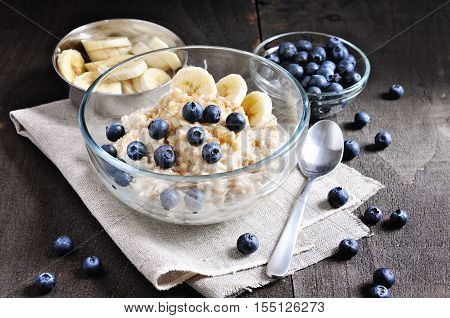 Oatmeal or porridge with blueberries bananas and brown sugar. Healthy breakfast. Toned image selective focus