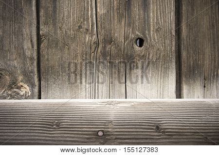 Looking thru a crack in the wood plank barn wall with a big knot