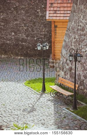 Bench for rest on the territory of the ancient castle with stone walls. Beautiful resting place