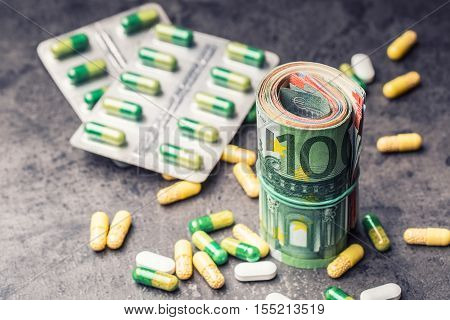 Euro money and medicaments. Euro coins and pills. Rolled euro banknotes stacked on each other in different positions and freely pills around scattered. Toned image.