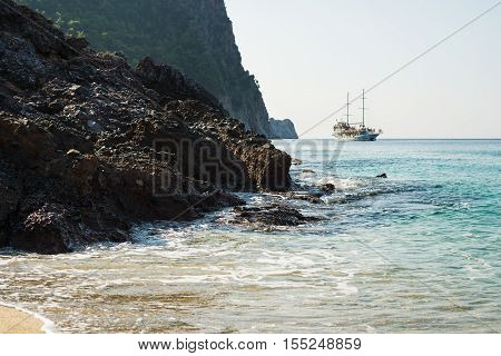 Natural rocks and pirate passenger ship sailing on Mediterranean sea near Kleopatra beach, Alanya, Turkey, Mediterranean coast