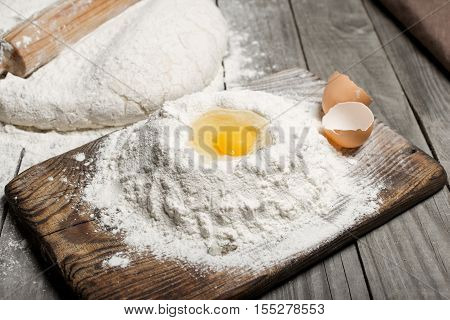 Egg yolk in the flour on wooden table in bakery.