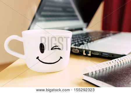 Smiling Cup, Notepad And Laptop On The Desk