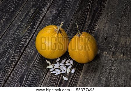 Pumpkin and pumpkin seeds. Dark background. Rustick wooden table.
