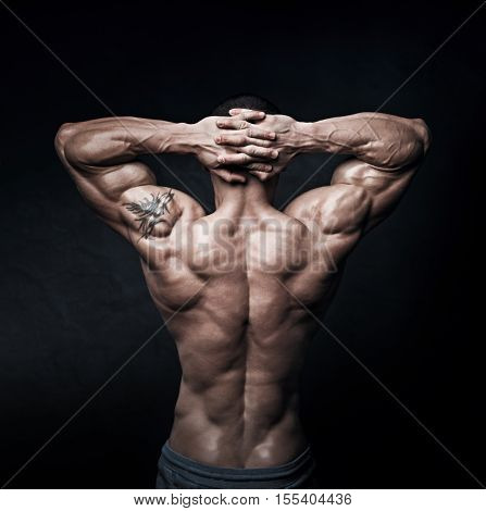 Strong athletic mans back on dark background. The concept of a complex imbroglio.