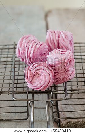 Homemade pink berry marshmallows - zefir on a baking rack. Wooden background.
