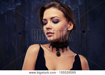 Beautiful young woman with smoky makeup looking down, wearing jewelry as a compositional element to the eveningwear, close-up shot