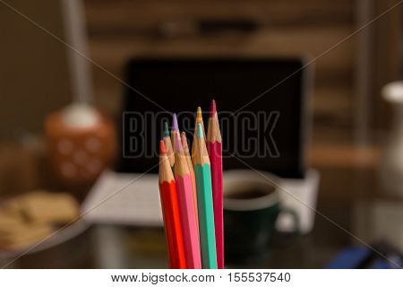 Design computer program. App for artists. Colored pencils close-up. The tablet and a cup of tea in the background