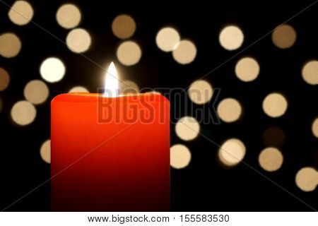 red candle close-up with christmas lights bokeh background