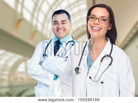 Two Male and Female Doctors or Nurses Standing Inside Hospital Building.
