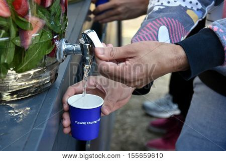 Man's hand unscrews the faucet which drops the fresh water into a glass. Filling A Glass Of Water From Tap. Jugs full of with water and fruits orange strawberry lemon.