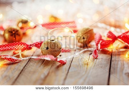 Metal Jingle Bells and Christmas Garland Light on wooden background. Christmas background