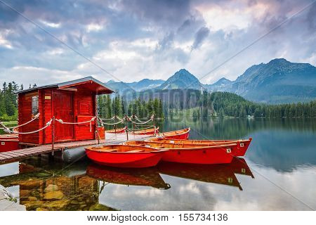 The picture captures the view of a person watching boats reverie calm lake fantastic mountains and the clouds floating across the sky