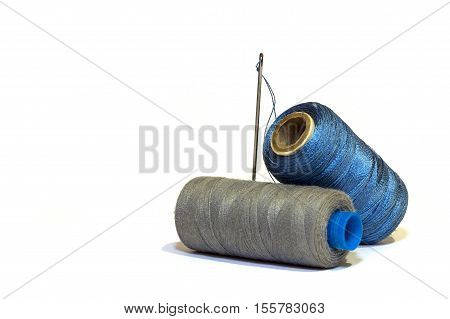 Grey and blue spools of thread and needle. insulation.