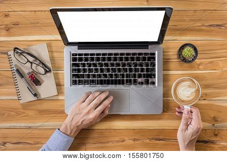 Young business man hands using laptop computer with blank screen and hand holding cup of coffee on office desk table with flashdrive pen glasses and leather notebook.View from above.Business concept.