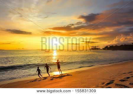 Happy children playing on beach Senggigi at the sunrise time. Island Lombok Indonesia.
