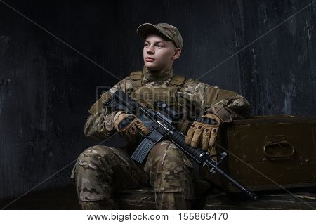 The soldiers - our pride. Special forces soldier with rifle on dark background. Modern soldier with rifle