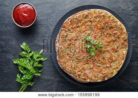 Lahmacun traditional turkish restaurant pizza with minced beef or lamb meat, paprika, tomatoes, cumin spice, parsley baked spicy middle eastern food on dark table background