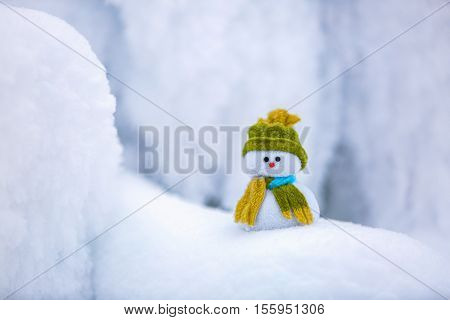 Incredible beautiful interesting white snow froze in strange textures forms and snowflakes and among all this beauty there is a little snowman in a hat and scarf.