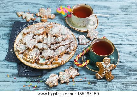 Christmas sweets baking gingerbread cookies on the plate. Decorated for Christmas gingerbread cookies christmas figurines bumps. Christmas cookies gingerbread on blue table tea drink. New Year food.