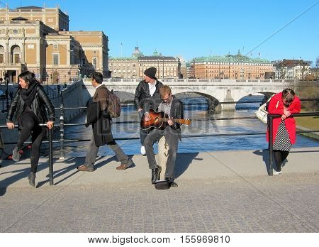 STOCKHOLM, SWEDEN - APRIL 14, 2010: People are playing the guitar and listening to music on The Riksbron Bridge. On The background is Norrbro Bridge and The Royal Swedish Opera