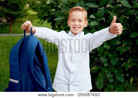 Young Elementary Schoolboy Carrying Backpack Making Thumb Up Gestures. Cheerful Child Standing Outdo
