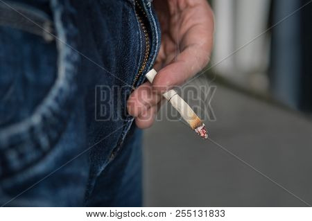 Guy Holds A Smoking Cigarette Butt From The Cigarette With Two Fingers.