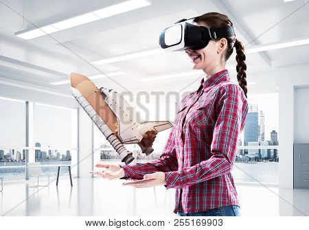 Young Caucasian Woman In Modern Office Interior Trying Virtual Reality Helmet And Viewing Space Shut