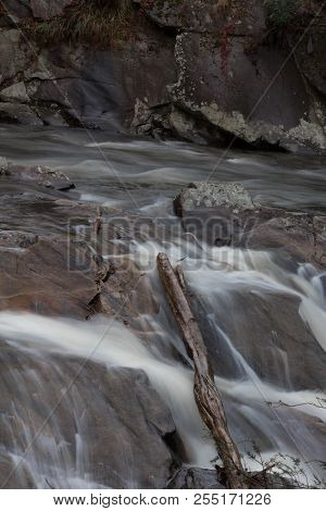 Deadfall Log Across Boulders In A Fast Moving Mountain Stream, Vertical Aspect
