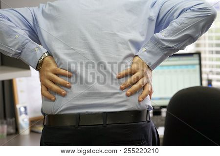 Close-up View Of A Office Worker Man With Pain In Kidneys. Young Male With Back Ache Clasping Her Ha