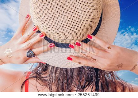 Woman With Golden Mehendi Tattoo And Red Manicure Holds Her Hat