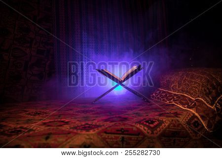 Open Holy Book Of Muslims On Stand On Eastern Carpet With Dark Toned Foggy Background. Muslim Religi
