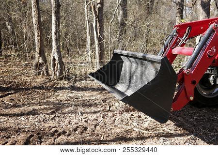 Tractor Front End Loader In Front Of Woods On Construction Side.