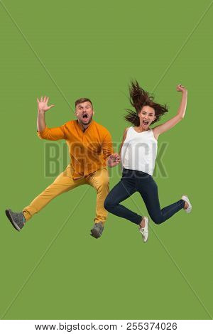 Freedom In Moving. Pretty Young Couple Jumping Against Green Background