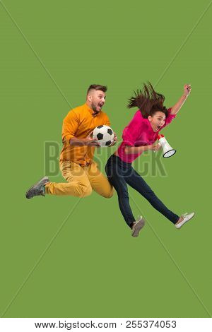 Forward To The Victory.the Young Couple As Soccer Football Player Jumping And Kicking The Ball At St
