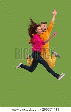 Full Length Of Young Couple With Mobile Phone While Jumping