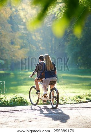 Back View Of Young Couple, Man And Blond Long-haired Woman Riding Tandem Double Bike Over The Edge O