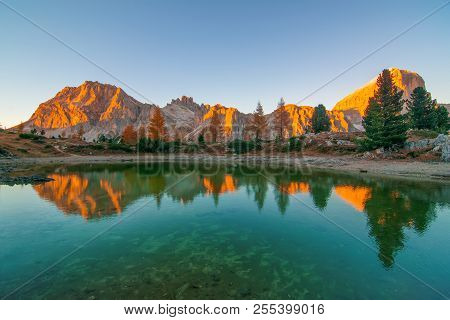 Mountain Rocks And Autumn Trees Reflected In Water Of Limides Lake At Sunset, Dolomite Alps, Italy