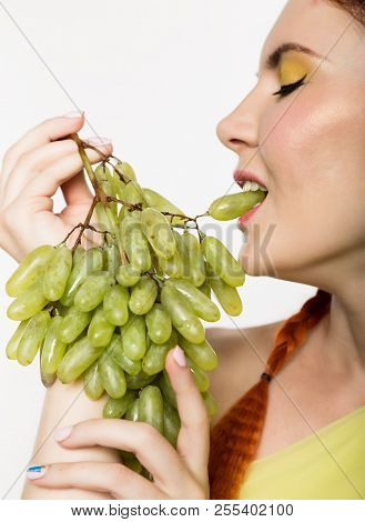 Beautiful Redhead Woman Is Eating Grapes. Concept Of Healthy Eating