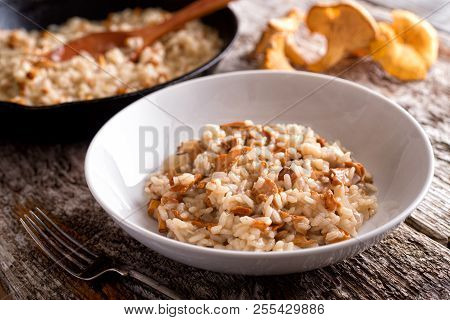 A Bowl Of Delicious Chanterelle Risotto On A Rustic Wood Table Top.
