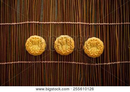 Traditional baked pastry mooncakes is eaten during the Mid-Autumn Festival. Flatlay on table, top down view low light with copy space. The Chinese character represent 