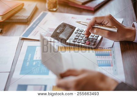 Businesswoman Using Calculator To Calculate Saving Account Passbook And Statement With Financial Rep