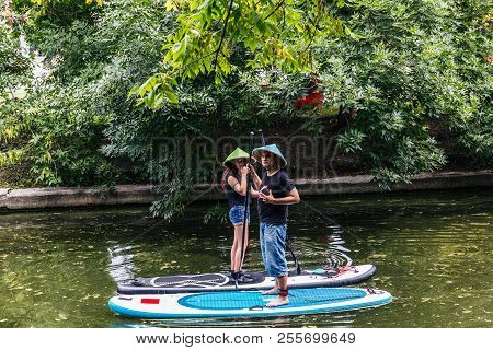 Moscow, Park On Krasnaya Presnya-july 05, 2018: A Young Girl And Man With A Paddle And In A Straw Ha