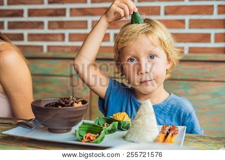 Boy Eats In A Cafe. Lifestyle. A Dish Consisting Of Rice, Fried Fish With Wood Mushrooms And Differe