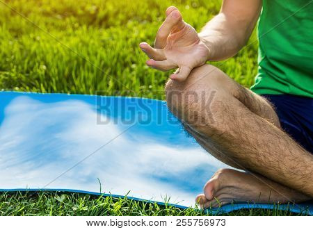 Seated Yoga Pose. Man Practicing Yoga Sitting On Mat In The Park. Healthy Active Lifestyle. Close-up