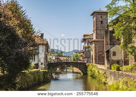 View Of The River Nive On Its Way Through The Village Of Saint Jean Pied De Port And In The Backgrou