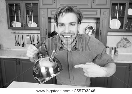 Happy Man In Blue Shirt Point Finger At Kettle. Kitchen Appliance And Furniture. Food Preparation, C