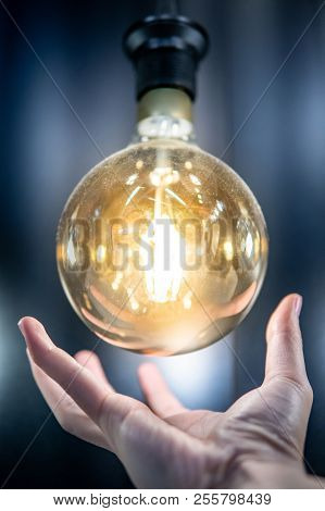 Male Hand Holding Illuminated Eleltric Light Blub. Energy Saving For Future. Concept Of Inspiration,