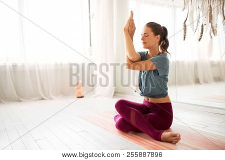 mindfulness, spirituality and healthy lifestyle concept - woman meditating at yoga studio