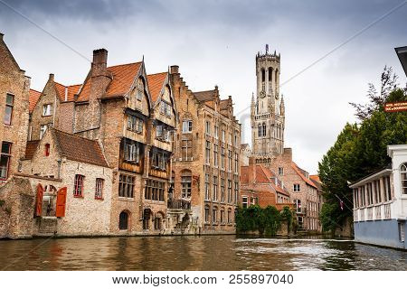Bruges, Belgium-august 15, 2015-the Belfry Tower And The Medieval Houses At The Canal In Brugge.